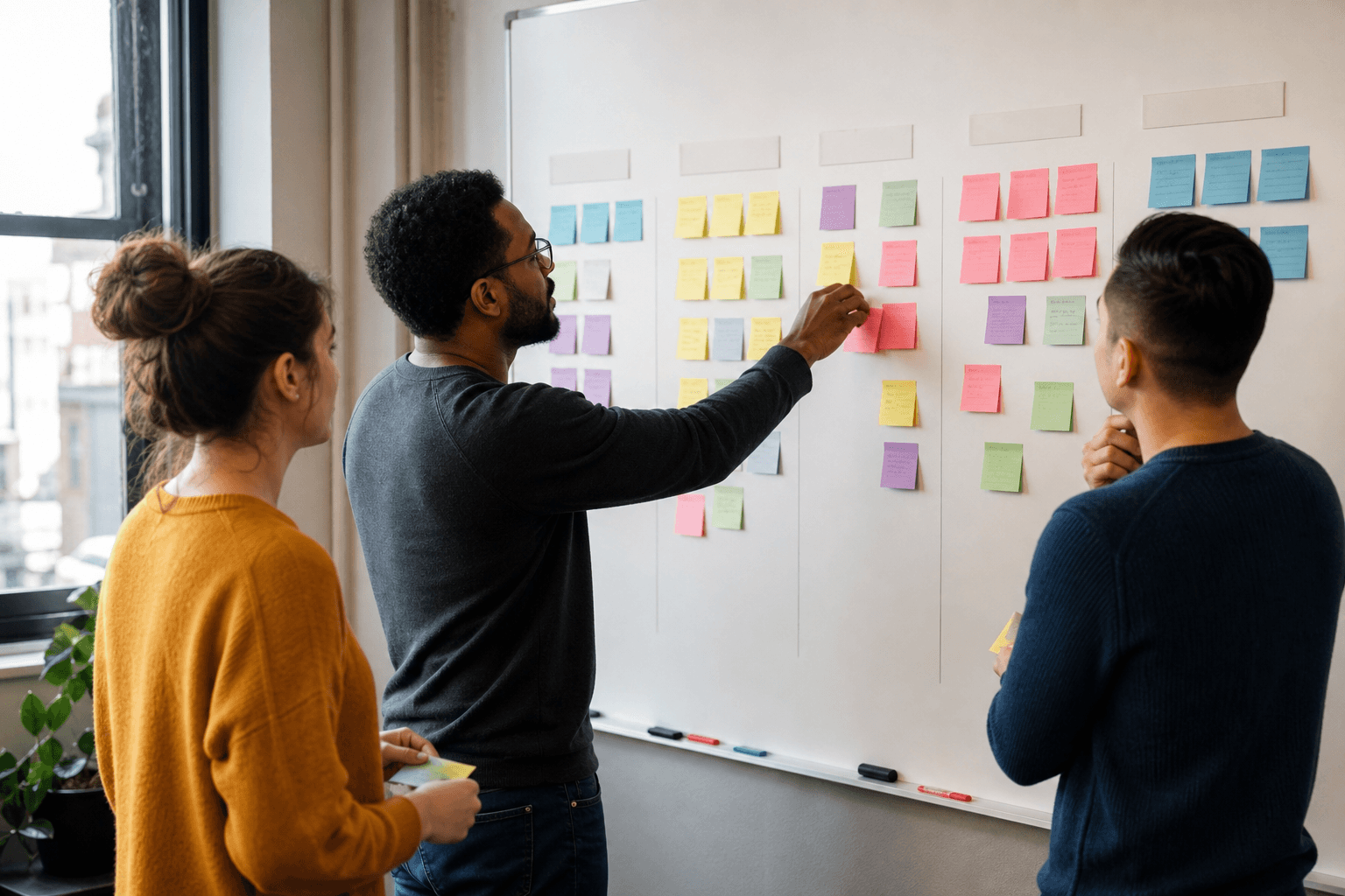 Nonprofit team building a program logic model on a whiteboard with sticky notes