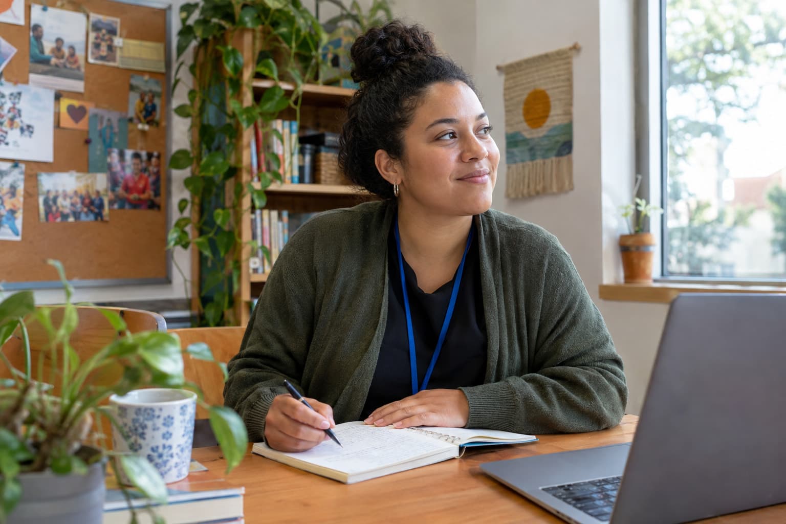 A staff member at a desk with a notebook beside a laptop