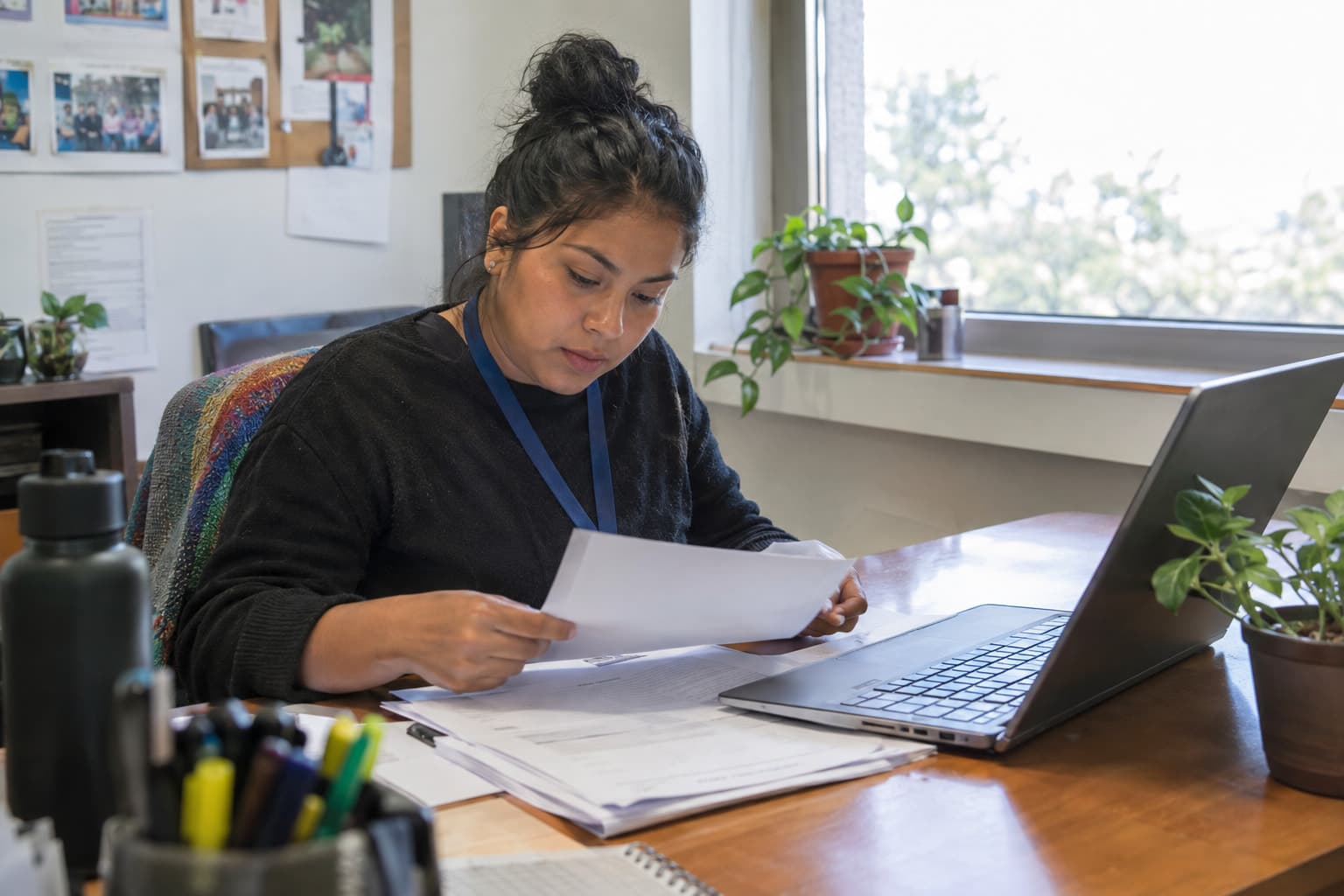 A staff member studying printed filings at a desk with a laptop