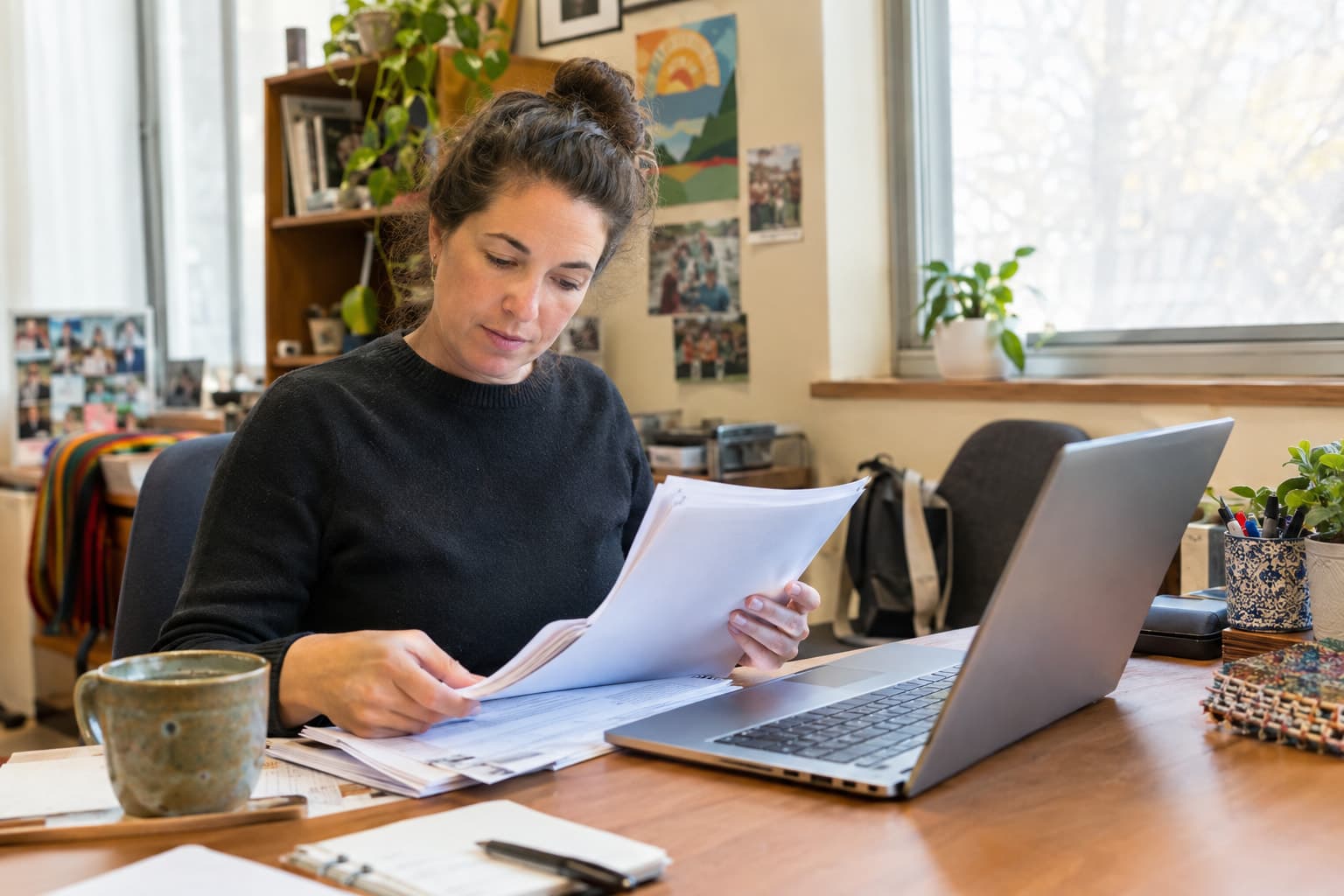 A grant writer at a laptop reviewing a long document