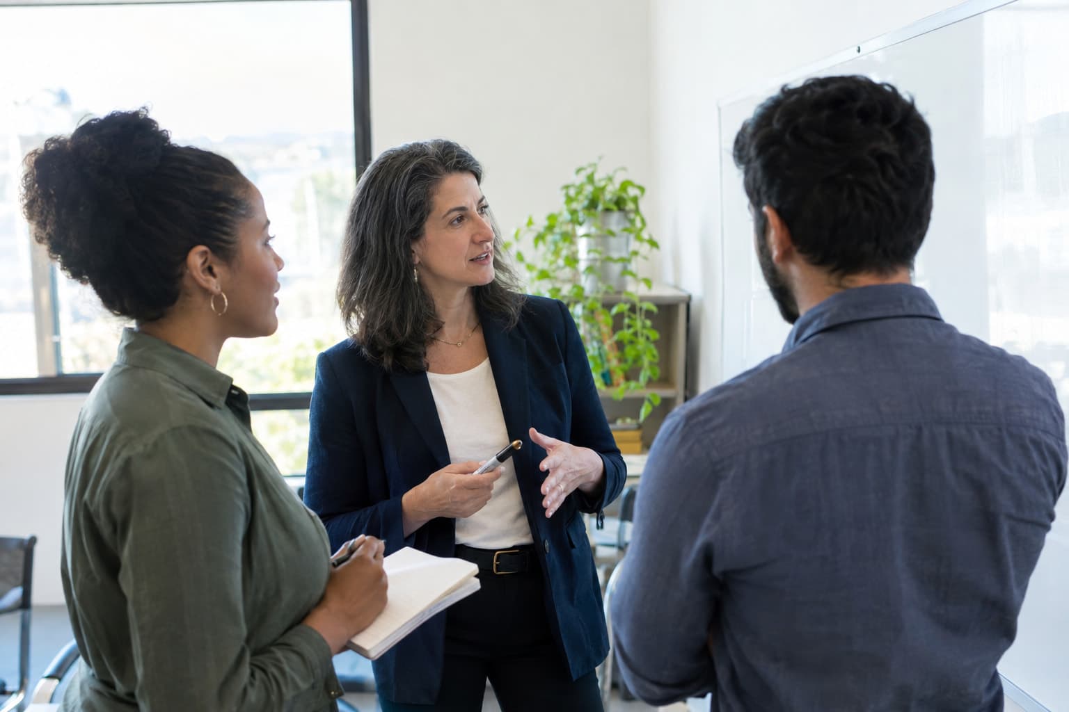 Three colleagues standing near an office whiteboard