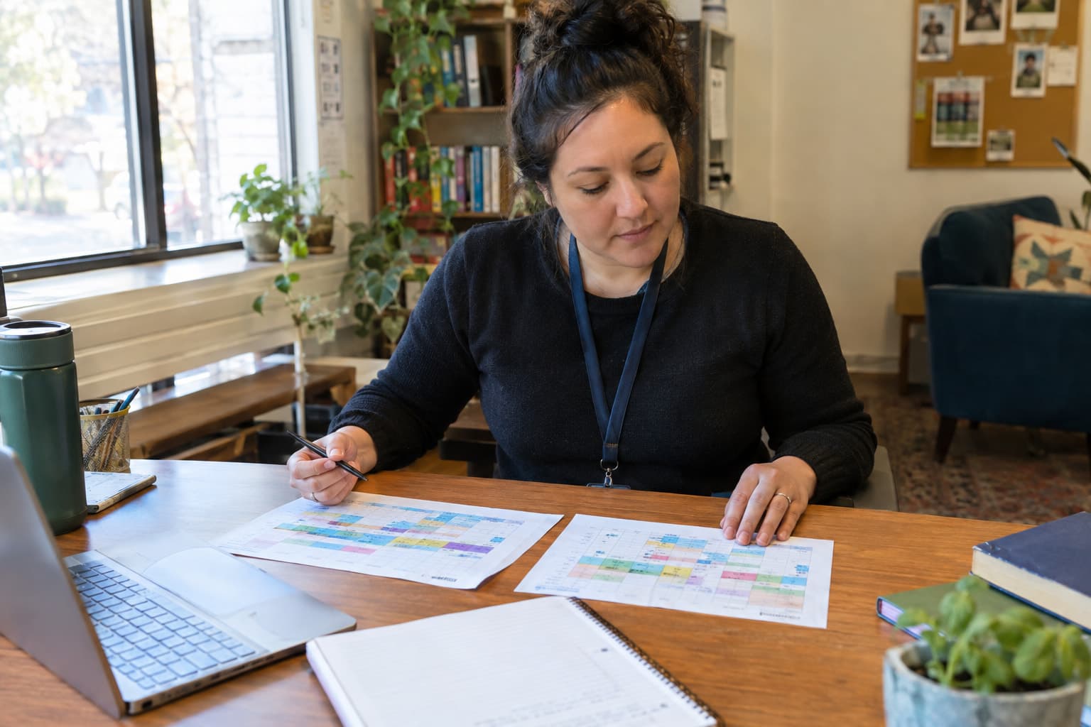 A nonprofit staff member comparing two printed schedules side by side at a desk