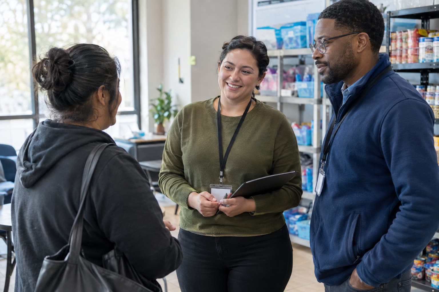 Two staff members speaking with a visitor in a program space with stocked shelves