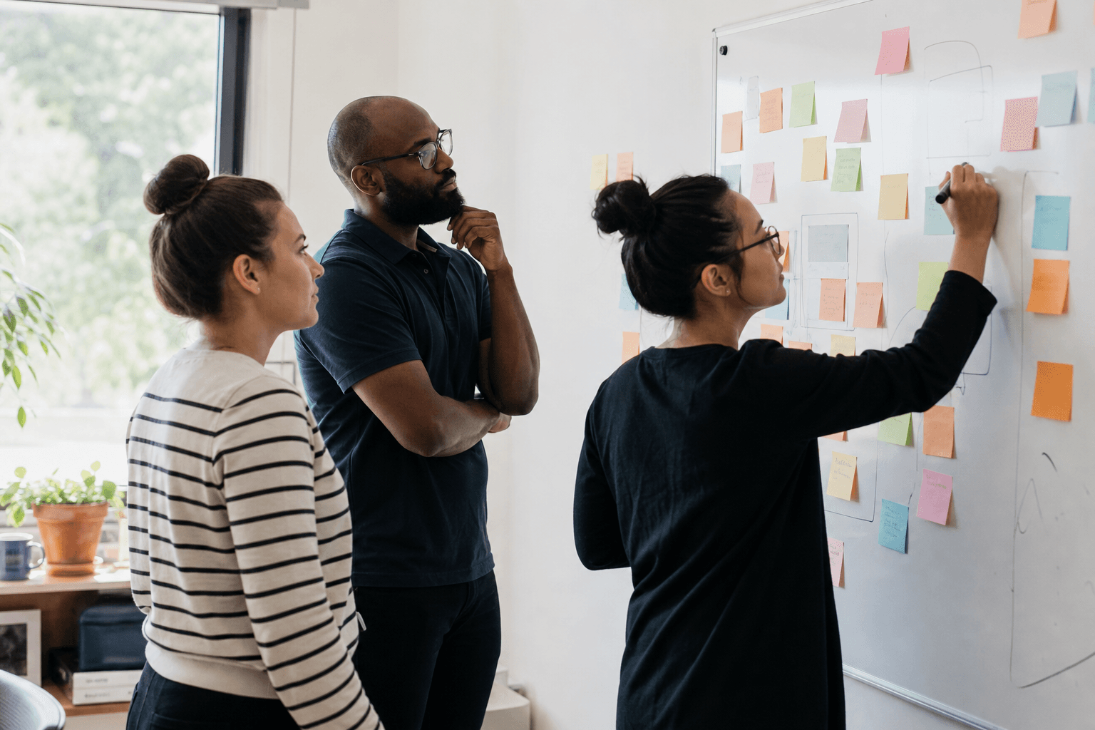 A nonprofit program team drafting project goals and objectives at a whiteboard
