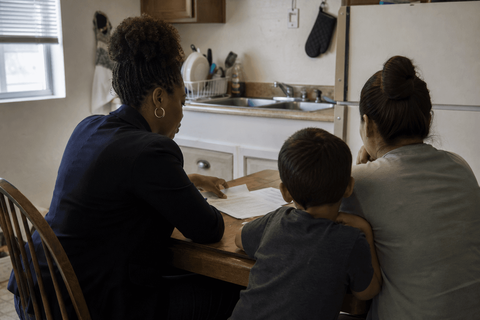 Housing case manager and a household reviewing a lease at a kitchen table