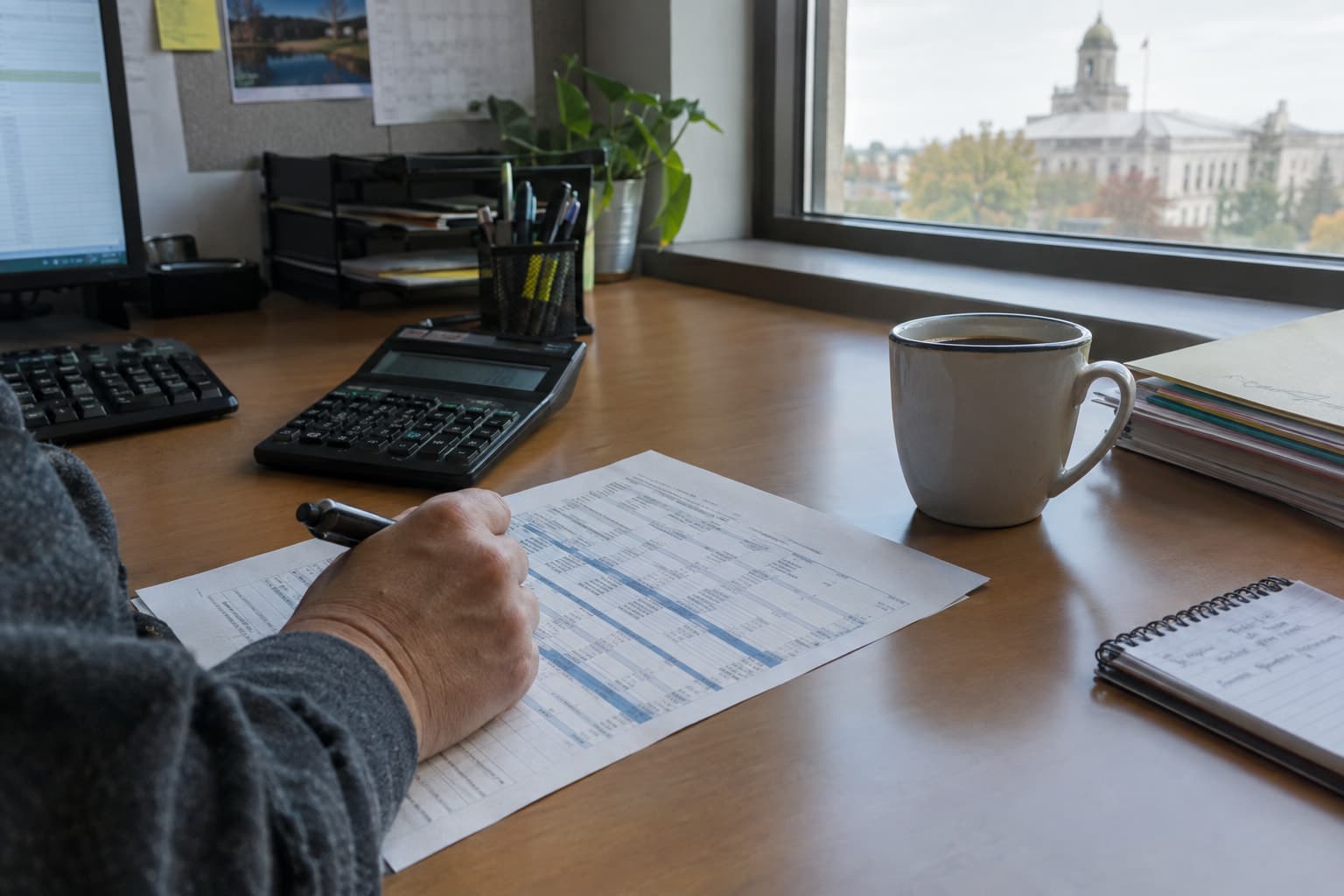 A calculator and a printed rate worksheet on a desk beside a coffee cup