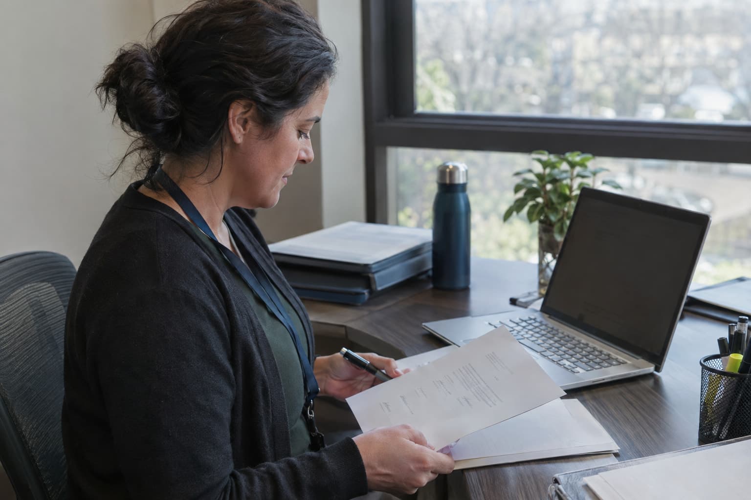 A research administrator reviewing a printed signature page beside a laptop