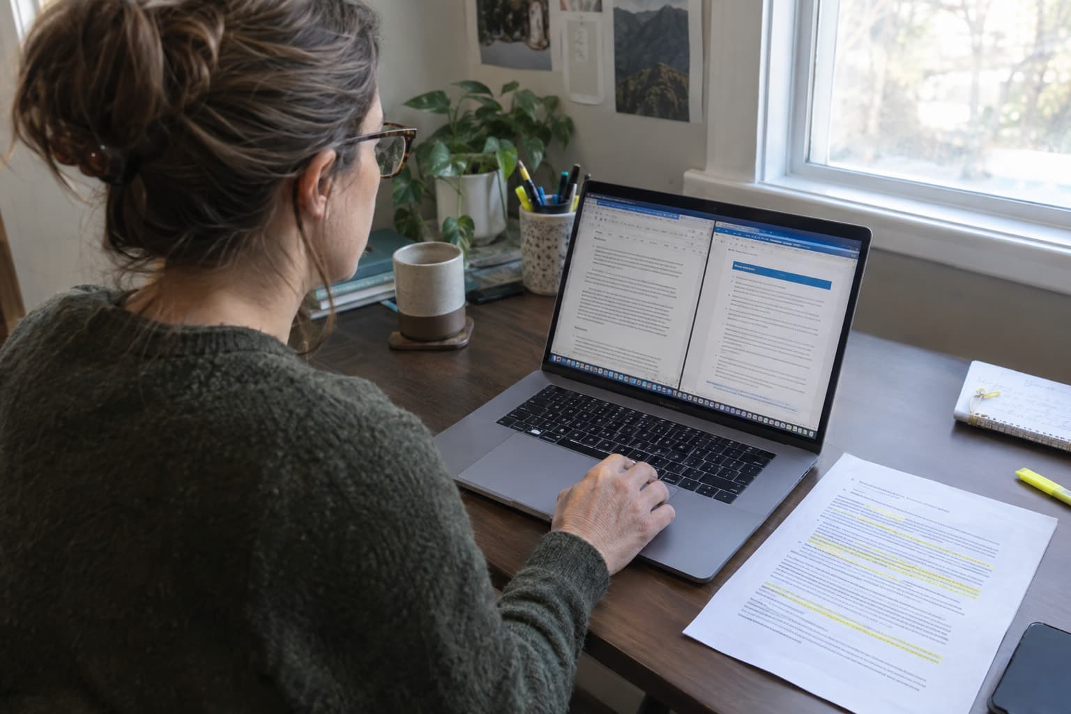 A grant writer copying a paragraph from one document window into another on a laptop