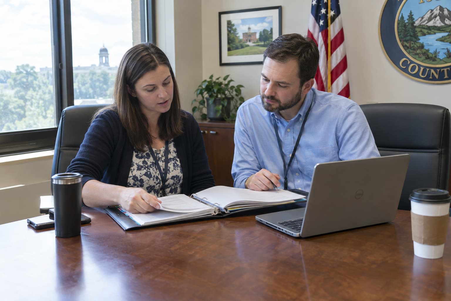A finance director and an auditor reviewing a binder at a conference table
