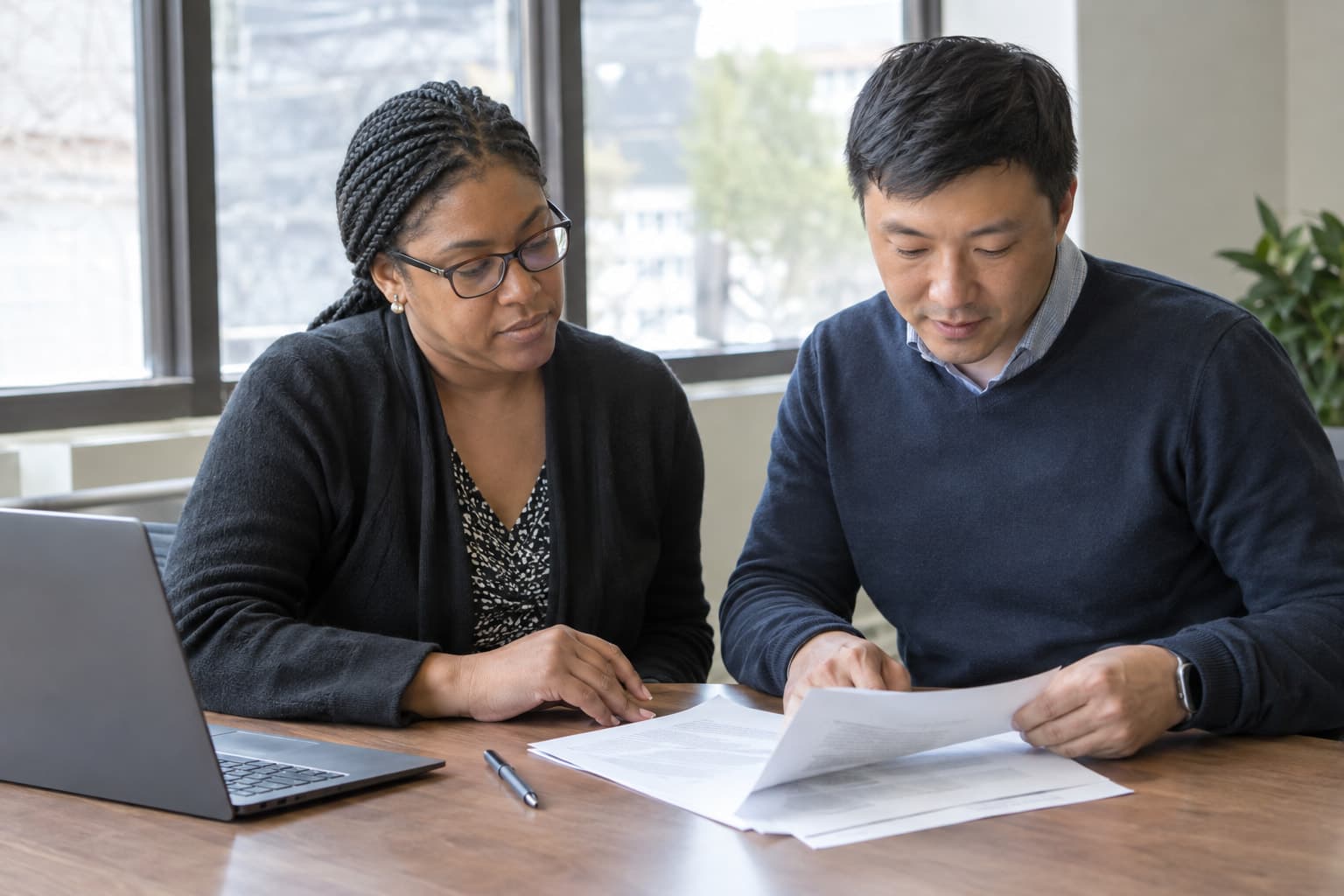 Two administrators at a table reviewing a printed agreement together